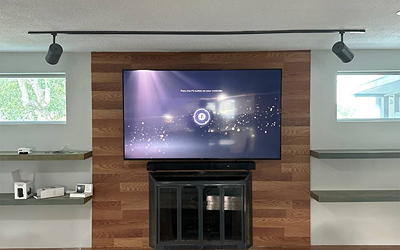 Large TV mounted over a fireplace with decorative wood paneling.