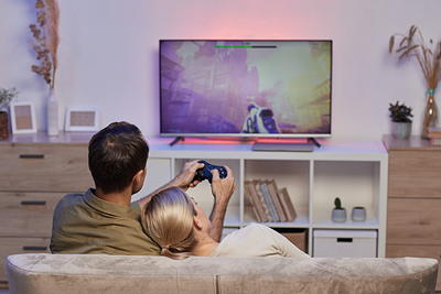 Couple gaming with colorful ambient LED backlighting behind their TV