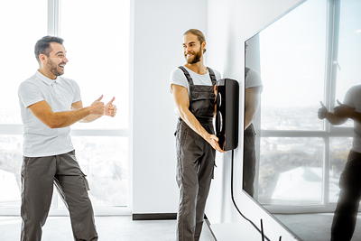 Technician installing a soundbar below a wall-mounted TV