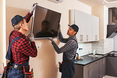 Two technicians carefully removing a wall-mounted TV — professional TV dismount service