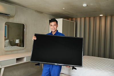 Technician holding a TV after dismounting it from the wall — safe TV removal service