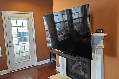 MantelMount TV retracted above fireplace mantel — clean, elevated position with hidden wires